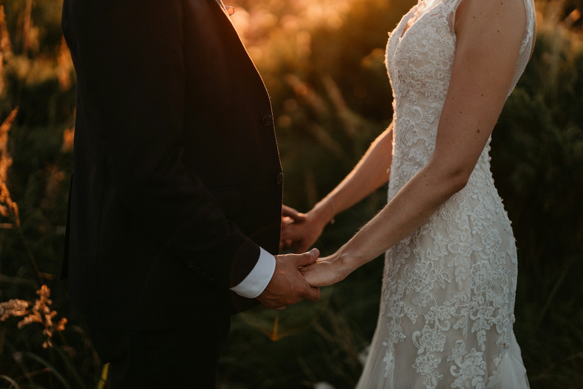PLACEHOLDER (Unsplash) — bride and groom holding hands at sunset
