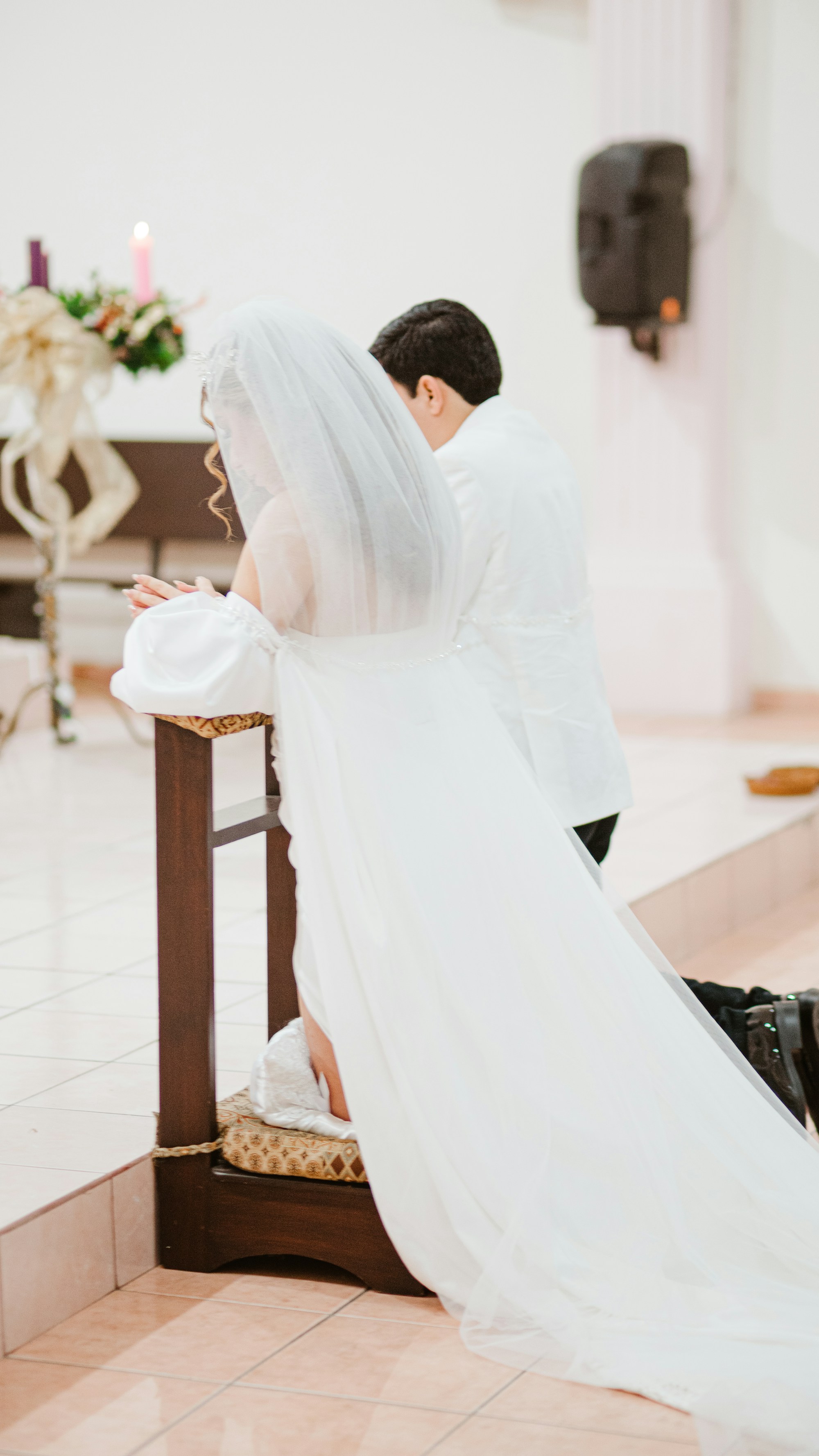 PLACEHOLDER (Unsplash) — bride and groom kneeling at the altar