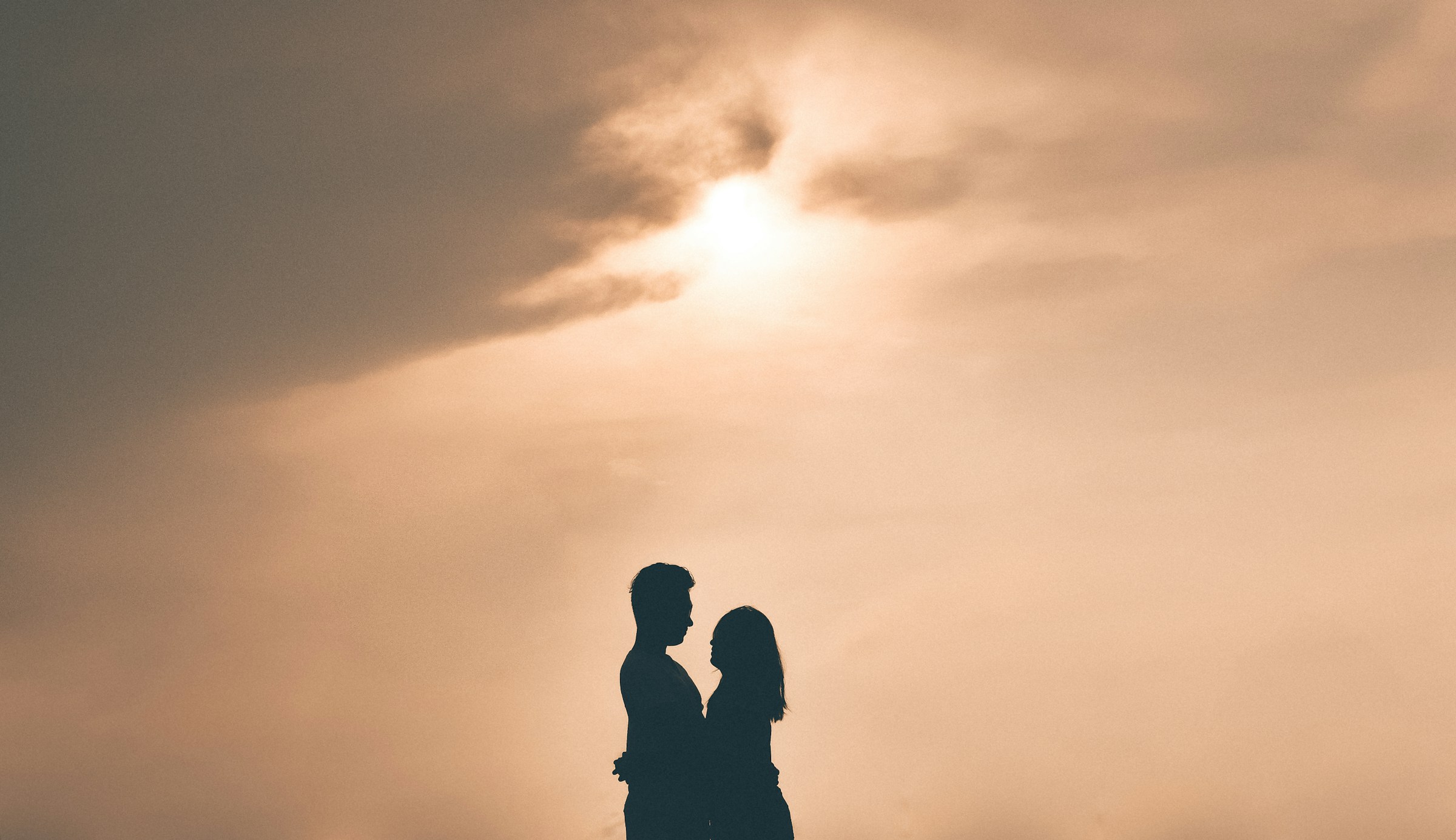 PLACEHOLDER (Unsplash) — silhouette of a couple hugging at golden hour