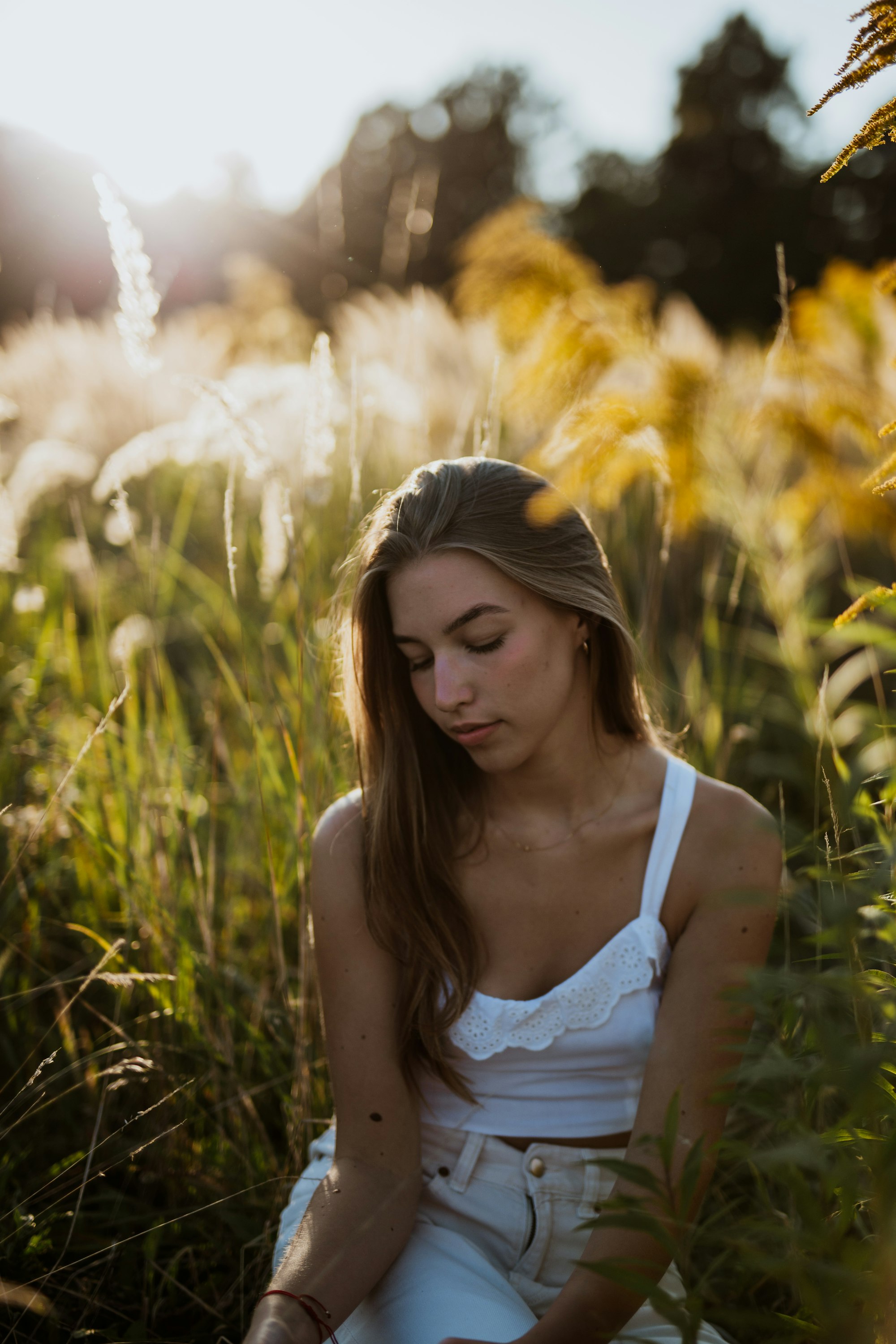 PLACEHOLDER (Unsplash) — young woman sitting in sunlit tall grass